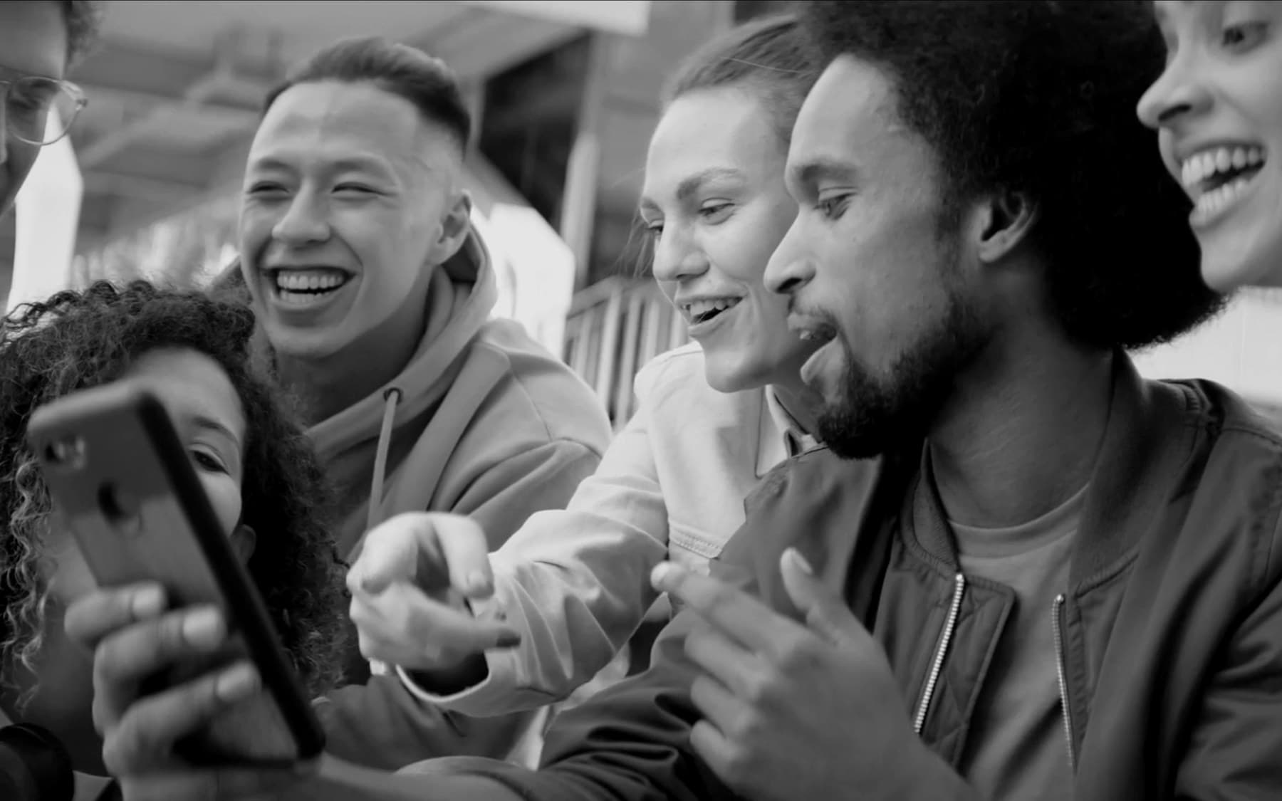 A group of friends sharing something on a phone — the power of word-of-mouth.