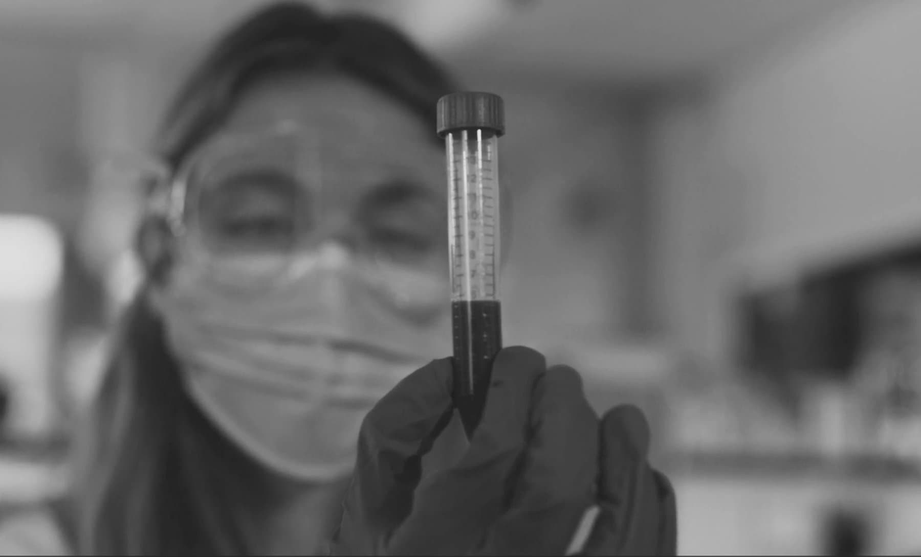 A lab technician holding a blood sample vial — the clinical precision behind every LifeVitals result.